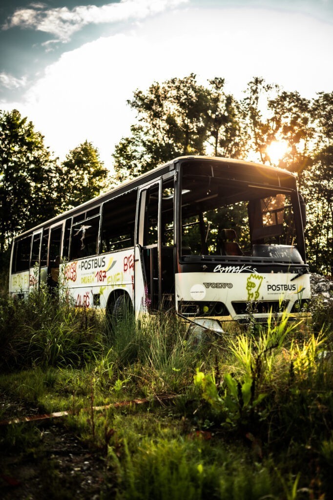 Street Art Fotografie mit altem Post-Bus auf Schrottplatz in Hallein bei Sonnenaufgang