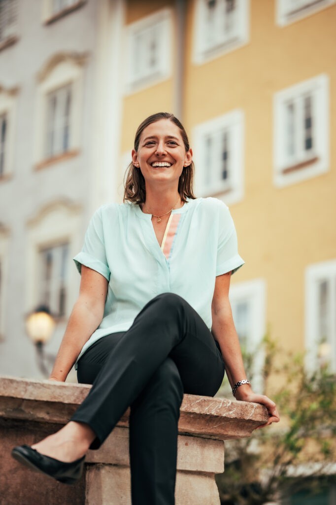 Portraitfoto der Immobilienmaklerin Marlene Springer am Brunnen am Korsteinplatz in Hallein