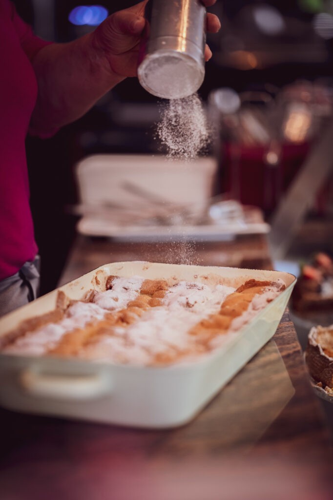 Frischer Kuchen wird in Eckzimmer Kaffee in Hallein mit Staubzucker bestreut