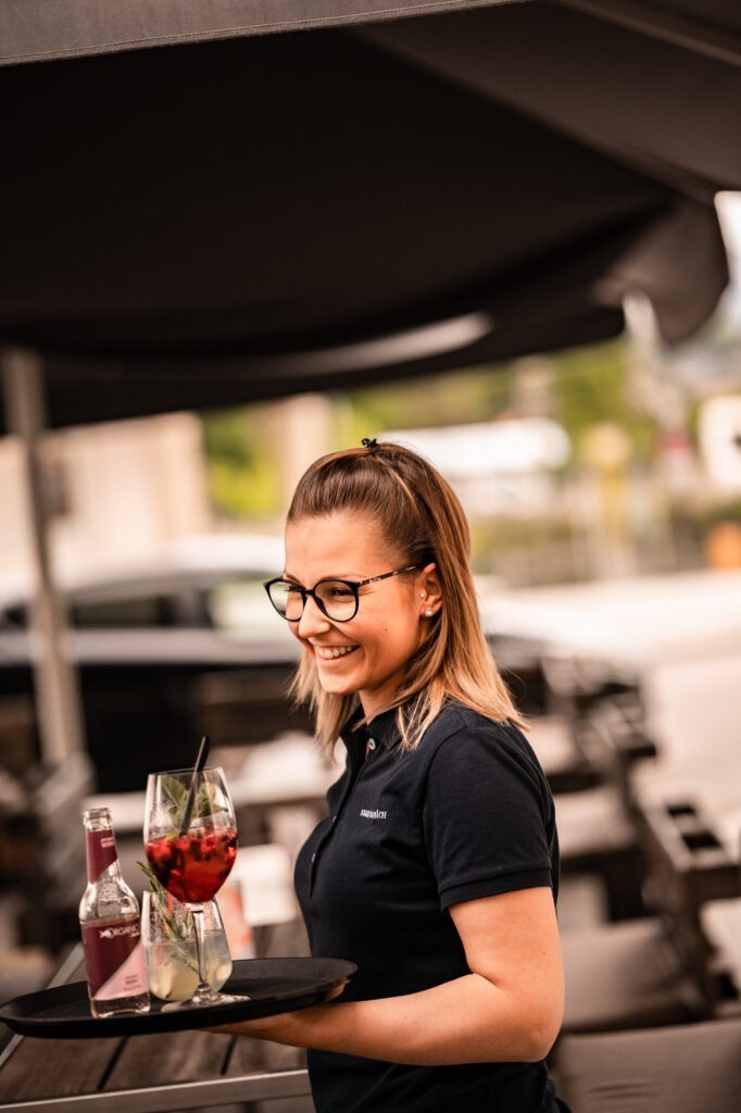 Inhaberin Jenny serviert Getränke auf Terrasse von Lokal Stadtgespräch Hallein